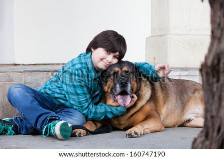 A 10 year old boy and his dog sitting down on the sidewalk