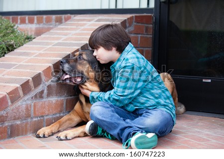 A 10 year old boy and his dog lying down on the sidewalkA 10 yeqr old boy and his dog sitting down on the sidewalk