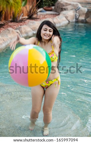 Cute young woman in a bikini playing in the pool