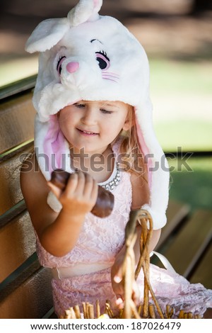 Cute  young girl in a Bunny hat smiling in the park holding a chocolate Easter Bunny