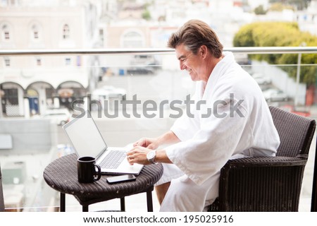 Attractive Man enjoying his morning coffee on his computer outside his hotel room