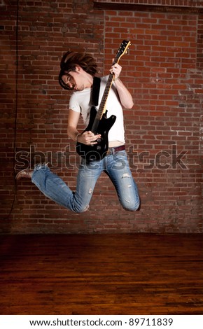 Male Guitar Player jumping with his electric guitar