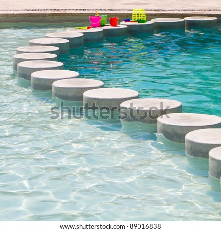 Resort Swimming Pool with the shallow water divided by deep water with stepping stones and children\'s toys along the top