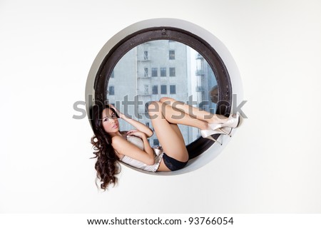 Pretty Hispanic Woman with Beautiful Long Hair sitting in the quiet space of a circle window