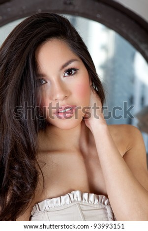 Pretty Sexy  Hispanic Woman with Beautiful Long Hair sitting in the a circle window with city buildings in the background