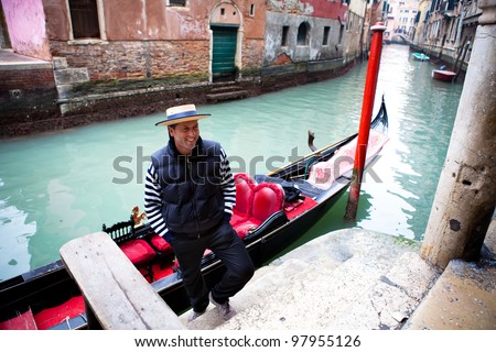 Gondolier welcoming tourist on a canal in Venice  by the Ancient Buildings and confetti on the ground from Carnival