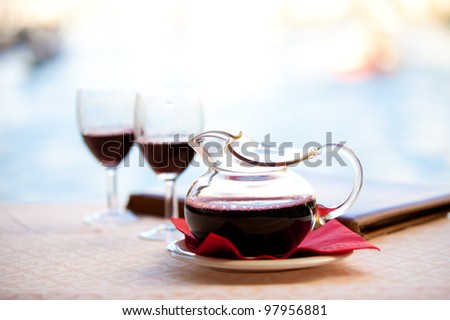 In Italy a Carafe a red wine - Chianti sits after being poured into glasses by the water under Rialto Bridge