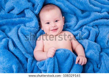 Happy little child wrapped in blue towel