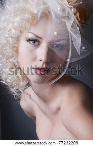 dark portrait of blonde girl in evening dress and a bowler hat with a veil