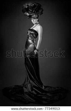 black and white Full-length dark portrait of a girl in a black dress and a rose hat.