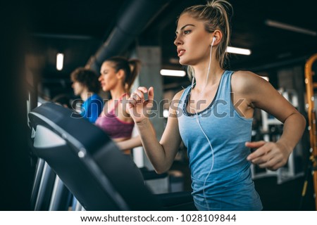 Young people running on a treadmill in health club.