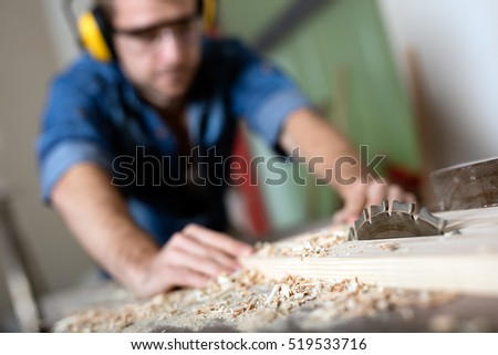Carpenter cutting wooden plank.