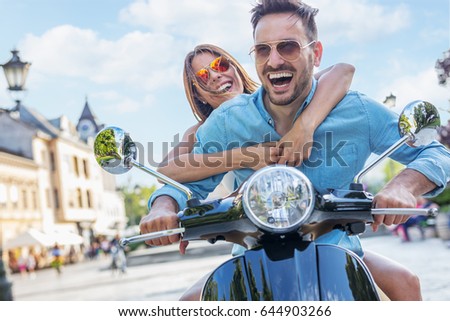 Scooter ride. Beautiful young couple riding scooter together. Focus on girl.