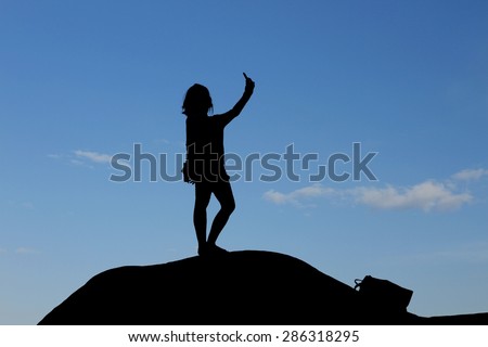 silhouette of woman take her photo by smartphone on top of the hill/silhouette selfie/silhouette of woman take her photo by smartphone on top of the hill
