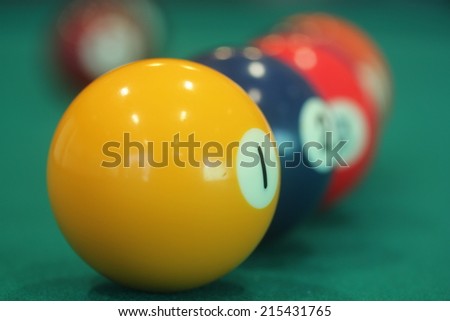 close up of yellow snooker ball with number one on it with other colorful balls in the background - leadership or leader or winner concept image