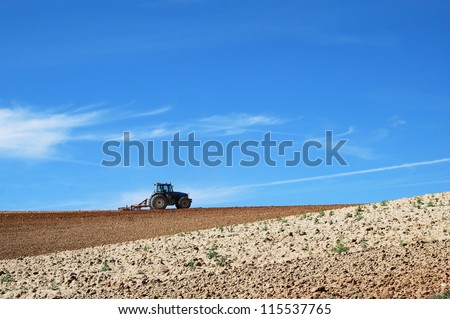 Tractor in the field, plowing a plot in summer.