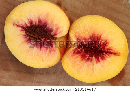 Peach cut in half on a wooden board