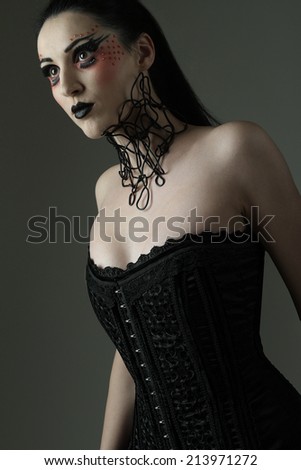 beautiful girl with black hair with artistic makeup and black lipstick in fetish and retro style, photographed in the studio