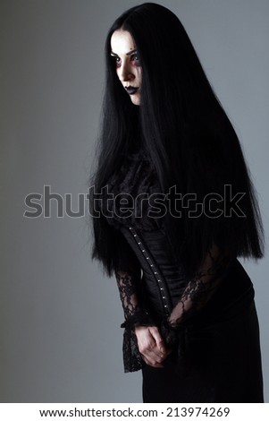 beautiful girl with black hair with artistic makeup and black lipstick in fetish and retro style, photographed in the studio