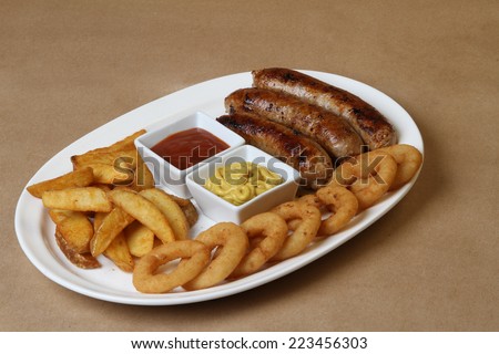 spicy American grilled sausages served on a white plate with two spicy sauces and delicious baked potatoes and crunchy onion rings ketchup  mustard