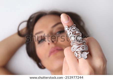 beautiful young brunette smiling girl showing lot of engagement rings and overjoyed by beautiful rings made of white gold with diamonds - showing middle finger