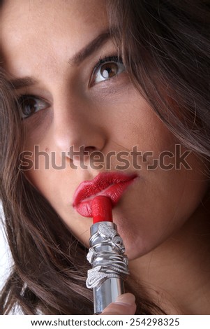 young beautiful brunette girl with beautiful lips with red lipstick full of optimism posing with red lipstick in hands where they slipped an engagement ring with a bright and shining diamonds
