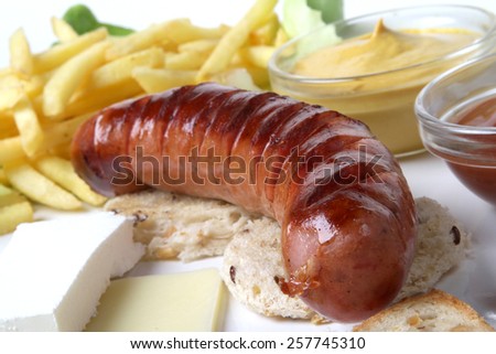 smoked pork sausage grilled on a white plate with a nice toast bread and baked egg and two kinds of cheese with fries and lettuce and red tomato ketchup and yellow mustard