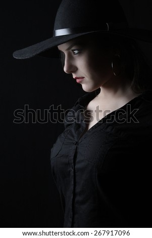 beautiful young brunette woman lady posing in a studio on a black background with old style hat