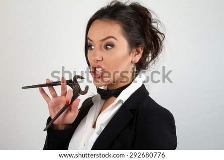 beautiful young brunette girl with tongue out trying to catch carpentry pliers own tongue with funny facial expressions
