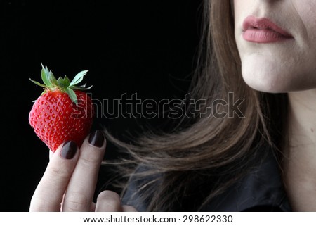 Girl and strawberries - beautiful young brunette with big breasts posing with a red fresh organic strawberries and seductive and sexy looking into the camera