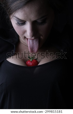 Girl and strawberries - beautiful young brunette with big breasts posing with a red fresh organic strawberries and seductive and sexy looking into the camera - facial expressions