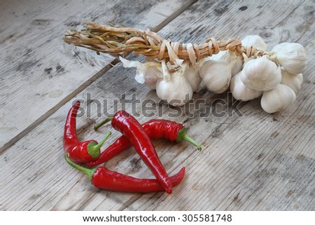 chili peppers and garlic - fresh organic red chili peppers and garlic clove in the domestic garden on a rustic wooden background