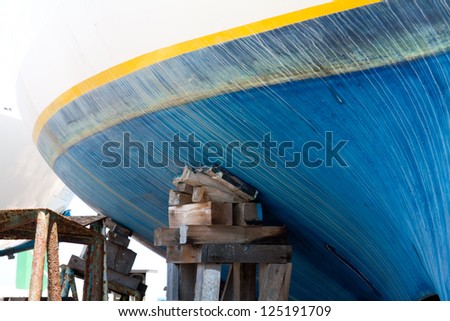 Sailing boats detail, with wood easel lifting the hull with white streams traces in blu hull