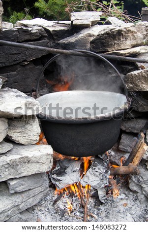 Old metal pot on the fire between stones outside