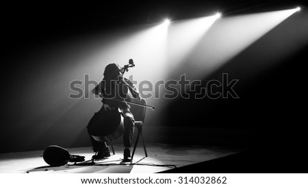 Silhouette cello player perform on stage with spotlight in monochrome,noise added