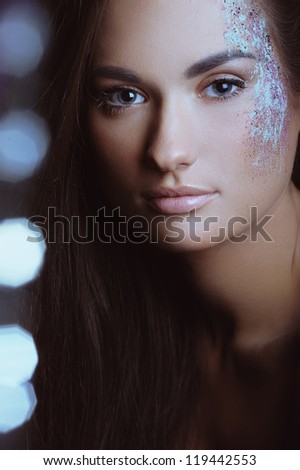 Beautiful girl with festive makeup in color spray powder and boke lights