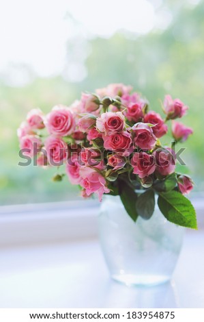 Bouquet of pink mini roses in vase on the window in the sunshine