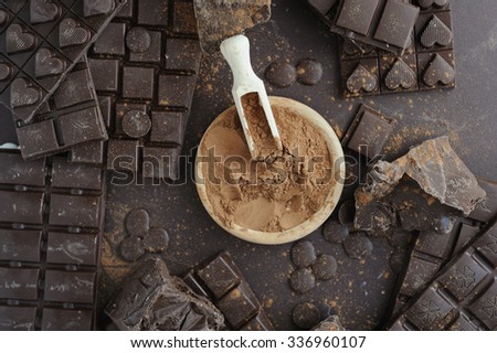 Bars, chopped and chips of  dark chocolate with cacao powder in wooden bowl