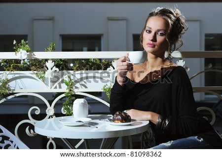 beautiful young woman sitting in a cafe eating cake and drink coffee