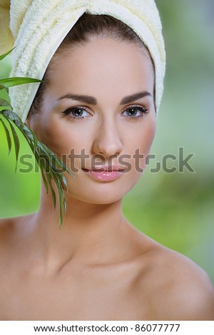 pretty healthy woman touches face green  tropical  leaf