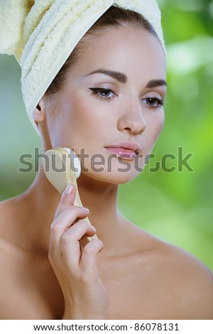 young beautiful woman cleans the face with a soft brush
