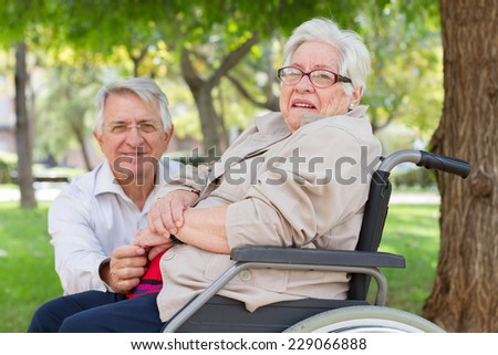 Portrait of a man and senior woman in wheel chair at the park. looking at camera with limited dof