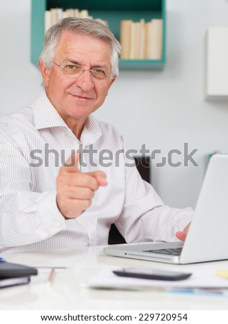 Mature man smiling working pointing at the camera