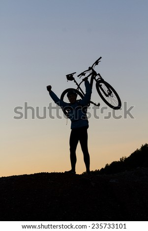 Silhouette of a cyclist with sunset celebrating making the top of the peak happy