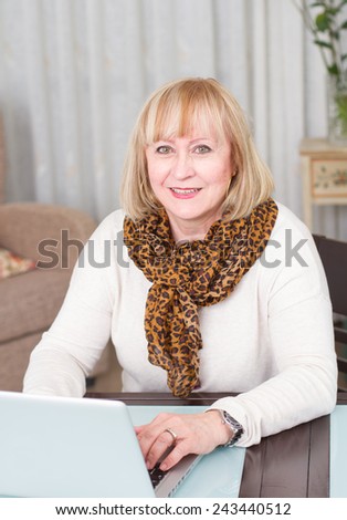 Middle age woman using computer at home. looking at camera