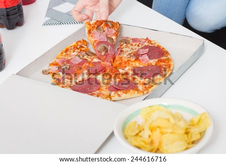 Pizza dinner. Hand grabbing a slice of pizza