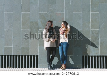 Friends standing and speaking in front of a stone wall