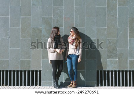 Friends standing and speaking in front of a stone wall