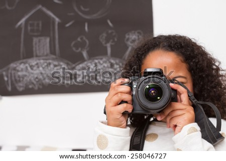 Little photographer. / Mixed child taking photos in a playroom with blackboard background