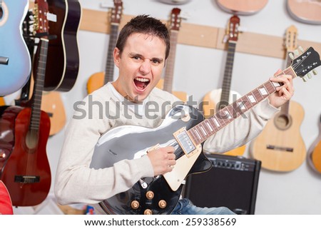 Man playing electric guitar while sing crazy in music shop